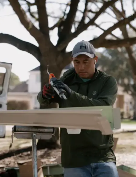 A roofer uses a hammer to install asphalt shingles